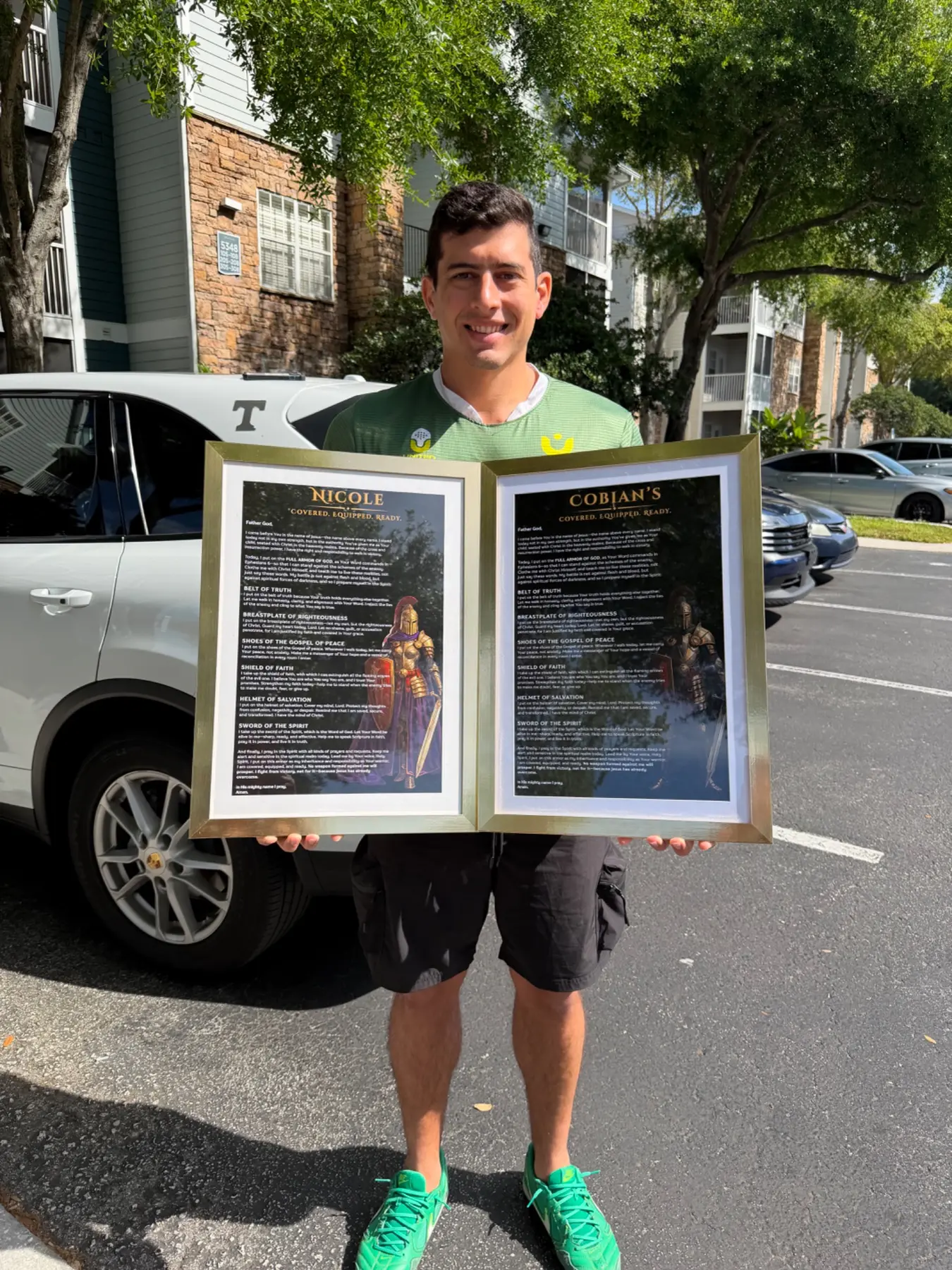 A man holding two personalized Armor of God prayers in gold frames